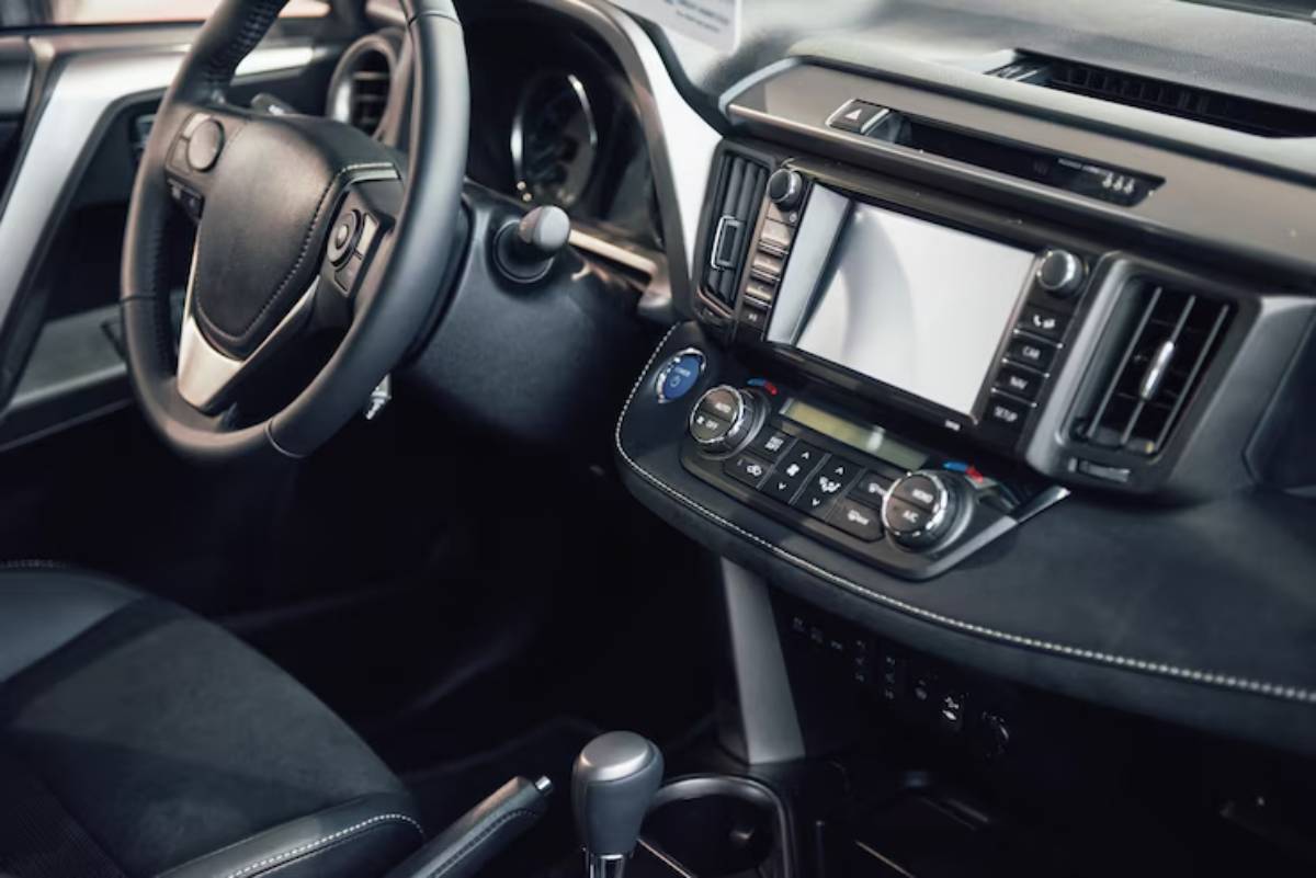 Interior view of a modern car showcasing the steering wheel, dashboard controls, and infotainment system with a sleek design.