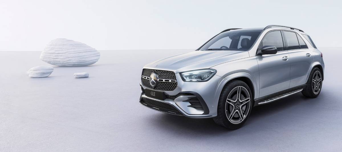 A sleek silver Mercedes GLE SUV is parked on a minimalist, light-colored surface with smooth white rocks in the background.
