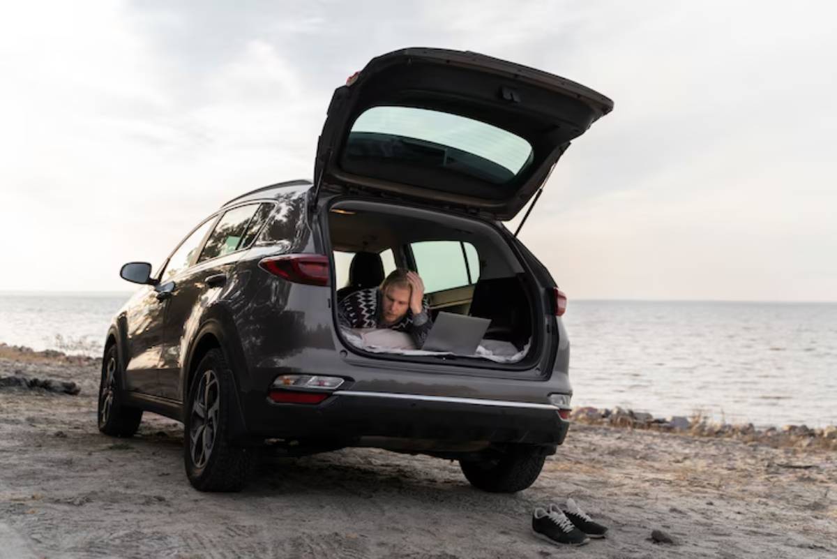 A gray SUV parked on a sandy beach, with its hatch open and a serene view of the water in the background.