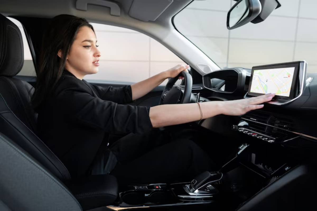 Inside a modern car, a person drives while reaching towards a touchscreen display showing a map, surrounded by sleek interior design.